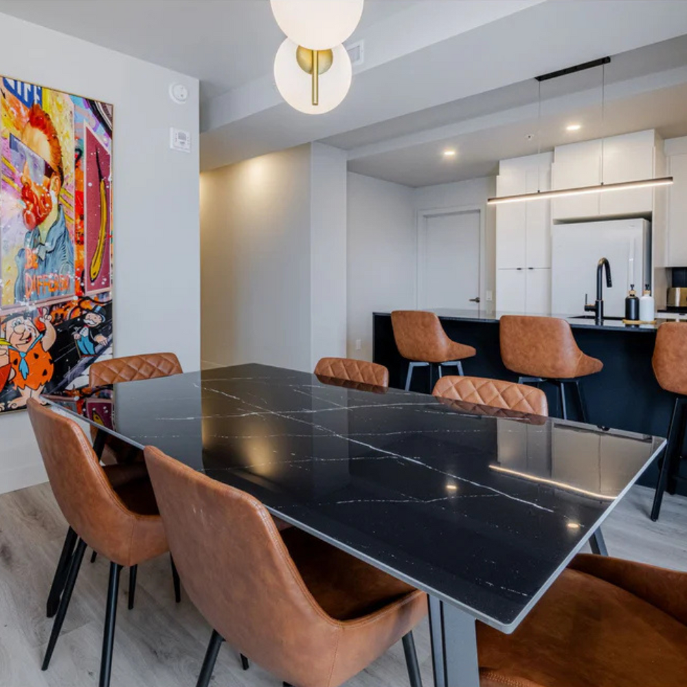 Modern dining area with a black marble table and brown chairs in a stylish kitchen.